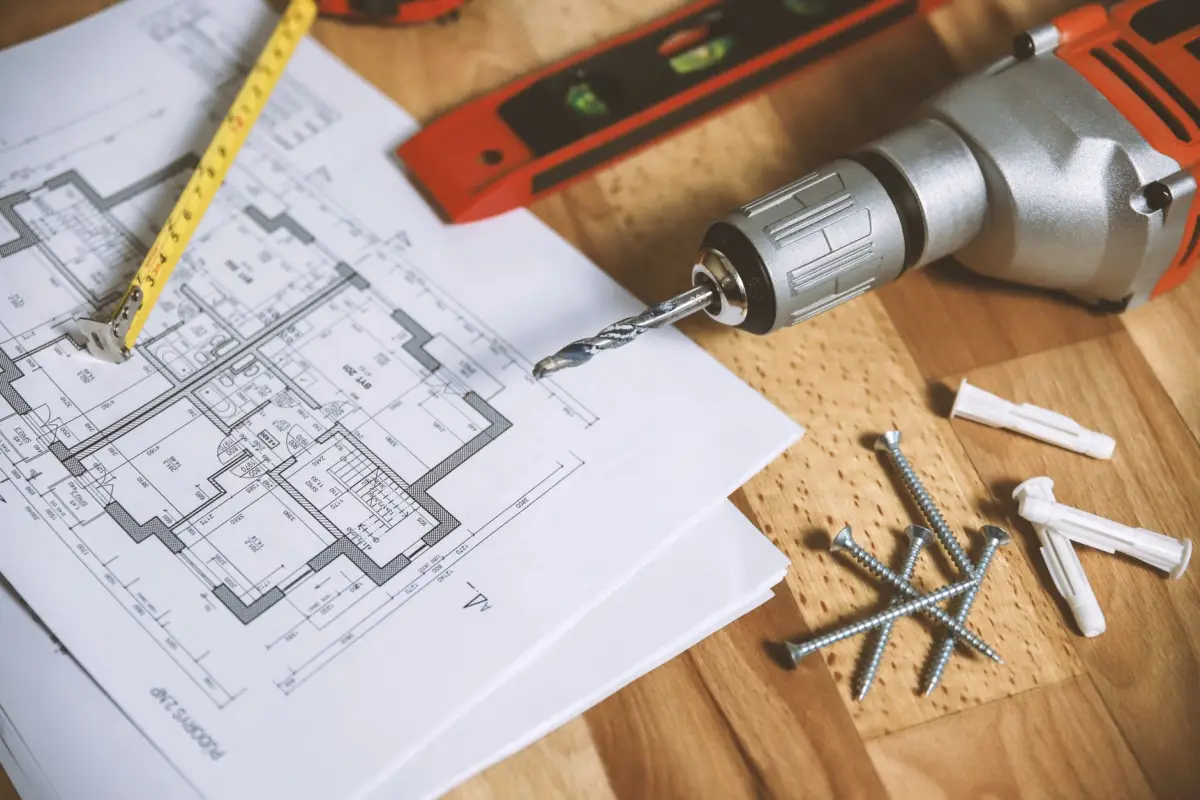 Plans et mètre ruban posés sur une table de travail dans un appartement en rénovation